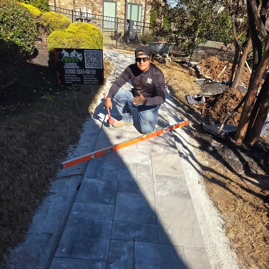 Owner of Lobos Landscape &amp; Hardscaper setting the edge course of a paver walkway in Cleveland, Tennessee
