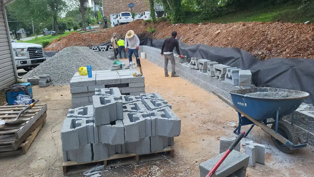 Crew laying retaining wall block with pallets staged on site in Cleveland, Tennessee