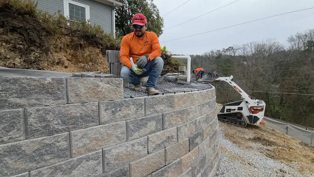 Lobos Landscape crew member on top of a finished block retaining wall in Cleveland, Tennessee
