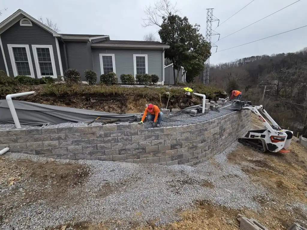 Curved block retaining wall going up behind a home in Cleveland, Tennessee
