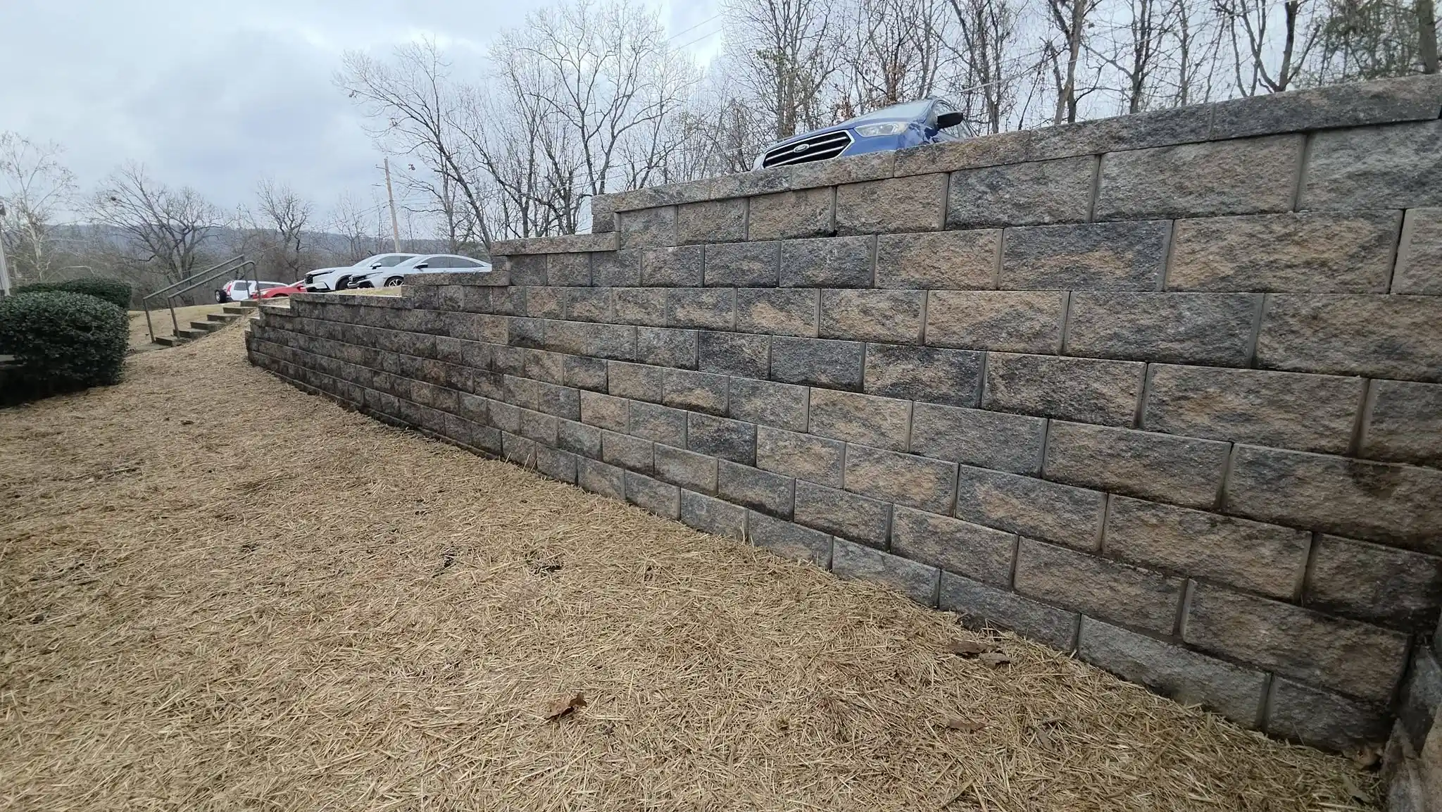 Long segmental block retaining wall running along a driveway, built by Lobos Landscape &amp; Hardscaper near Cleveland, Tennessee