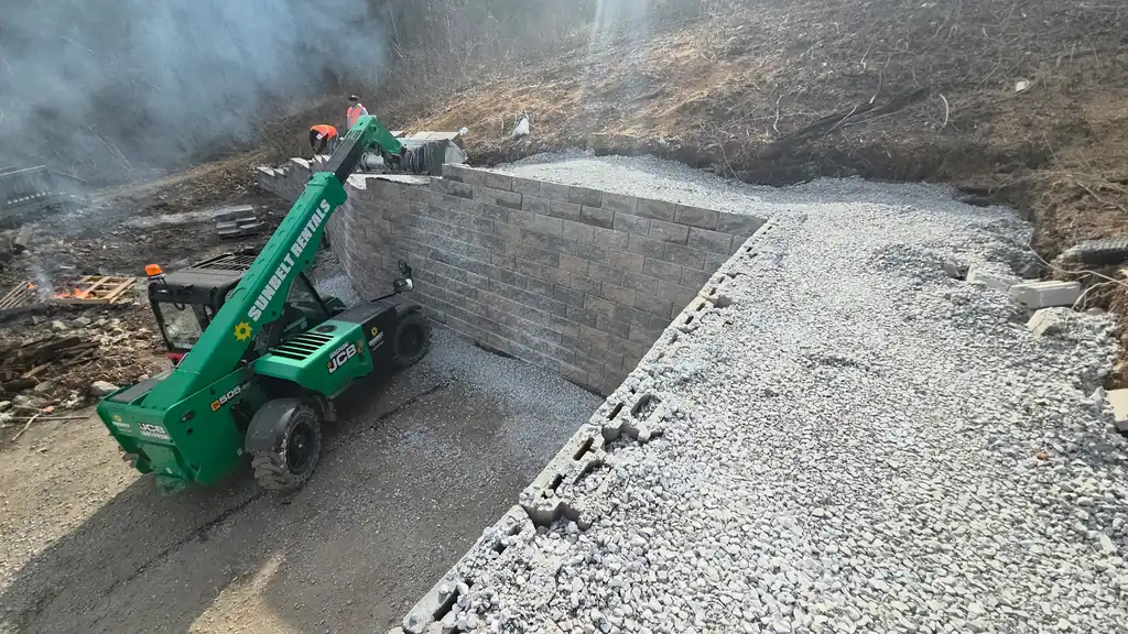 Telehandler setting retaining wall block along a freshly cut bank in Cleveland, Tennessee